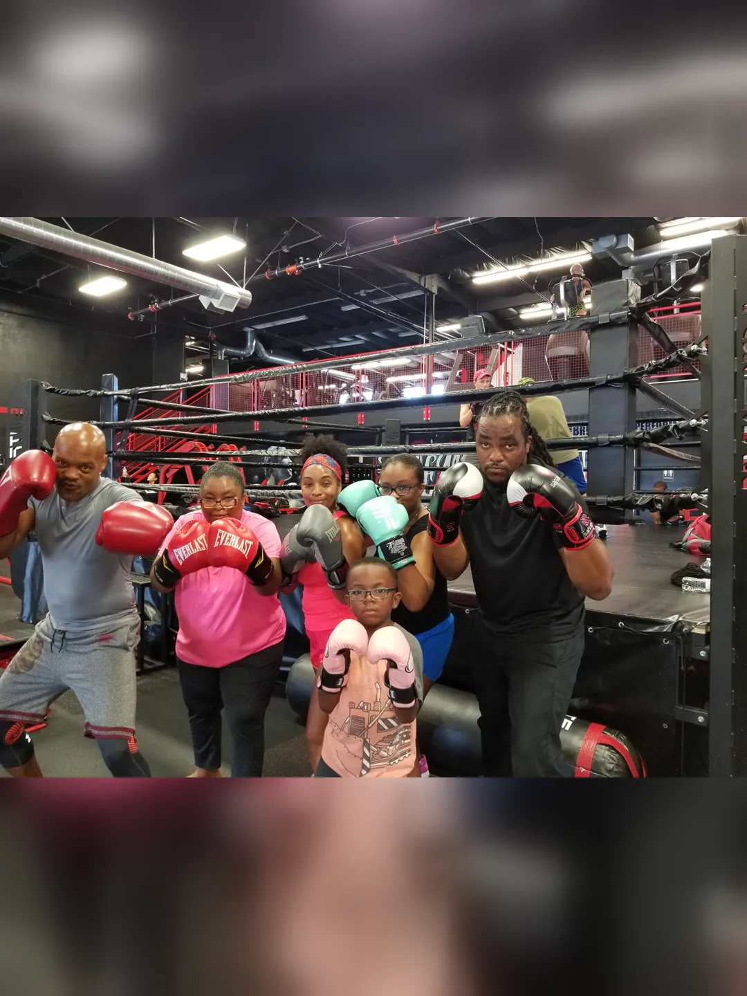 Coach Bizz and a family of fighters posing ringside with their gloves up