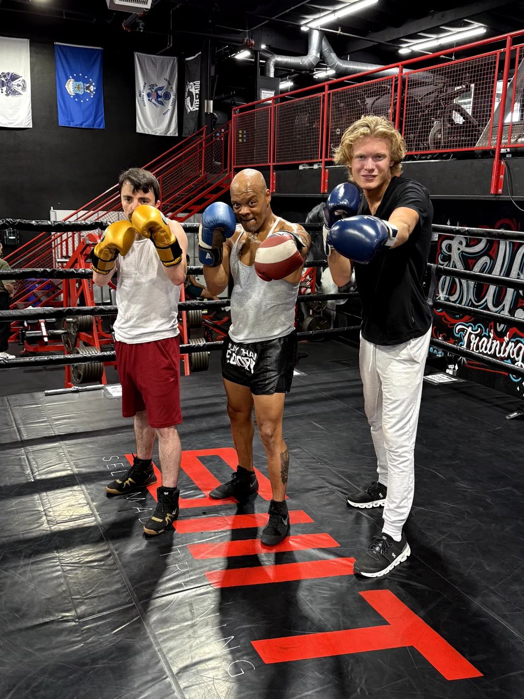 Coach Bizz in the ring between two of his fighters, gloves up
